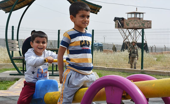 Sınırda asker eli tetikte görev yapıyor, çocuklar ise parkta oynuyor