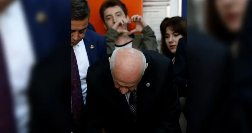 Devlet Bahçeli oy kullanırken arkasındaki genç 'kalp' yaptı