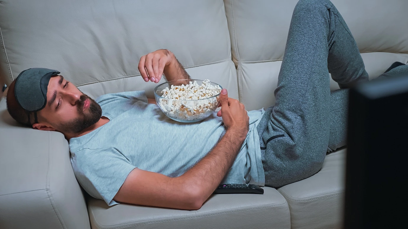 tired-man-relaxing-sofa-front-television-eating-popcorn-while-watching-movie-show-482257-21535.webp