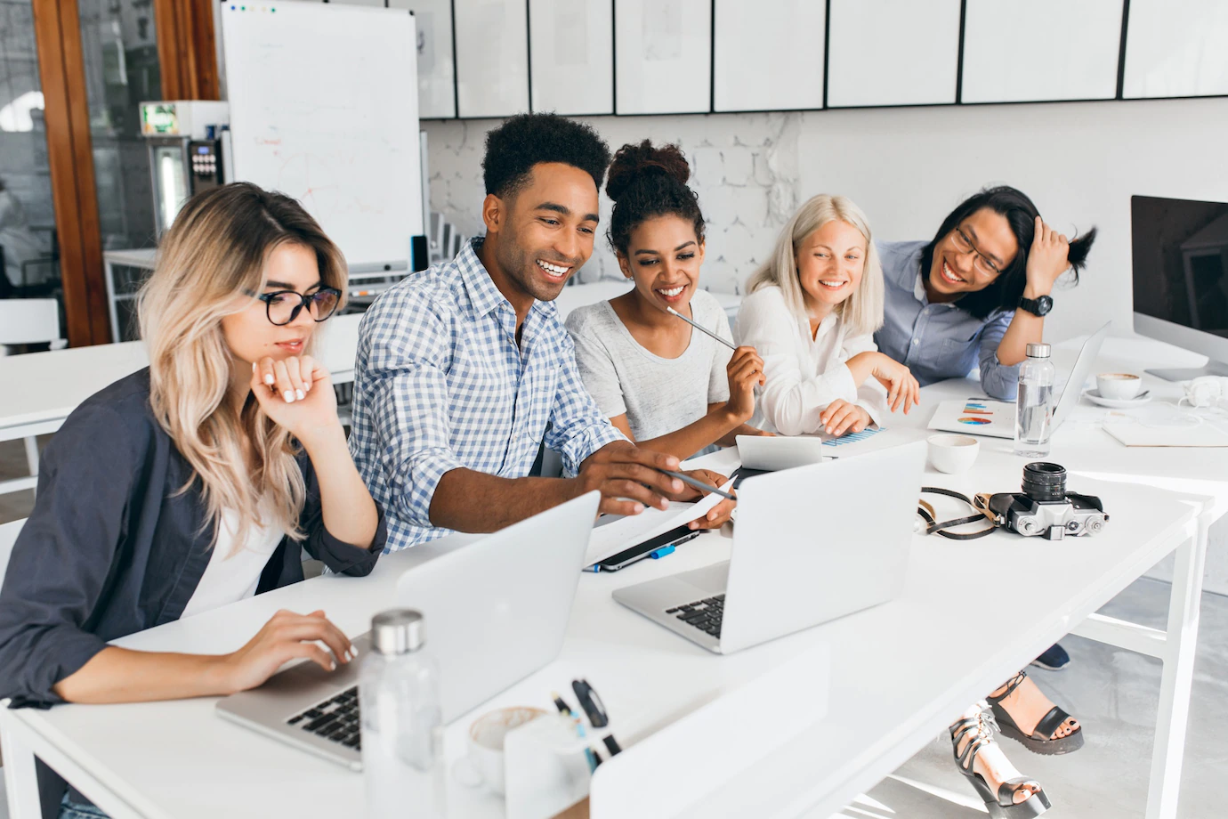 smiling-african-student-pointing-with-pencil-laptop-screen-concentrated-blonde-woman-glasses-propping-chin-with-hand-while-working-with-computer-office-197531-3714.webp