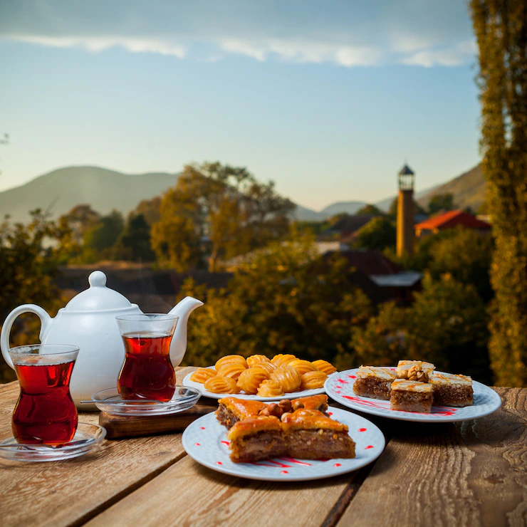 some-turkish-desserts-with-glasses-tea-teapot-table-with-village-background-side-view-176474-3946.webp