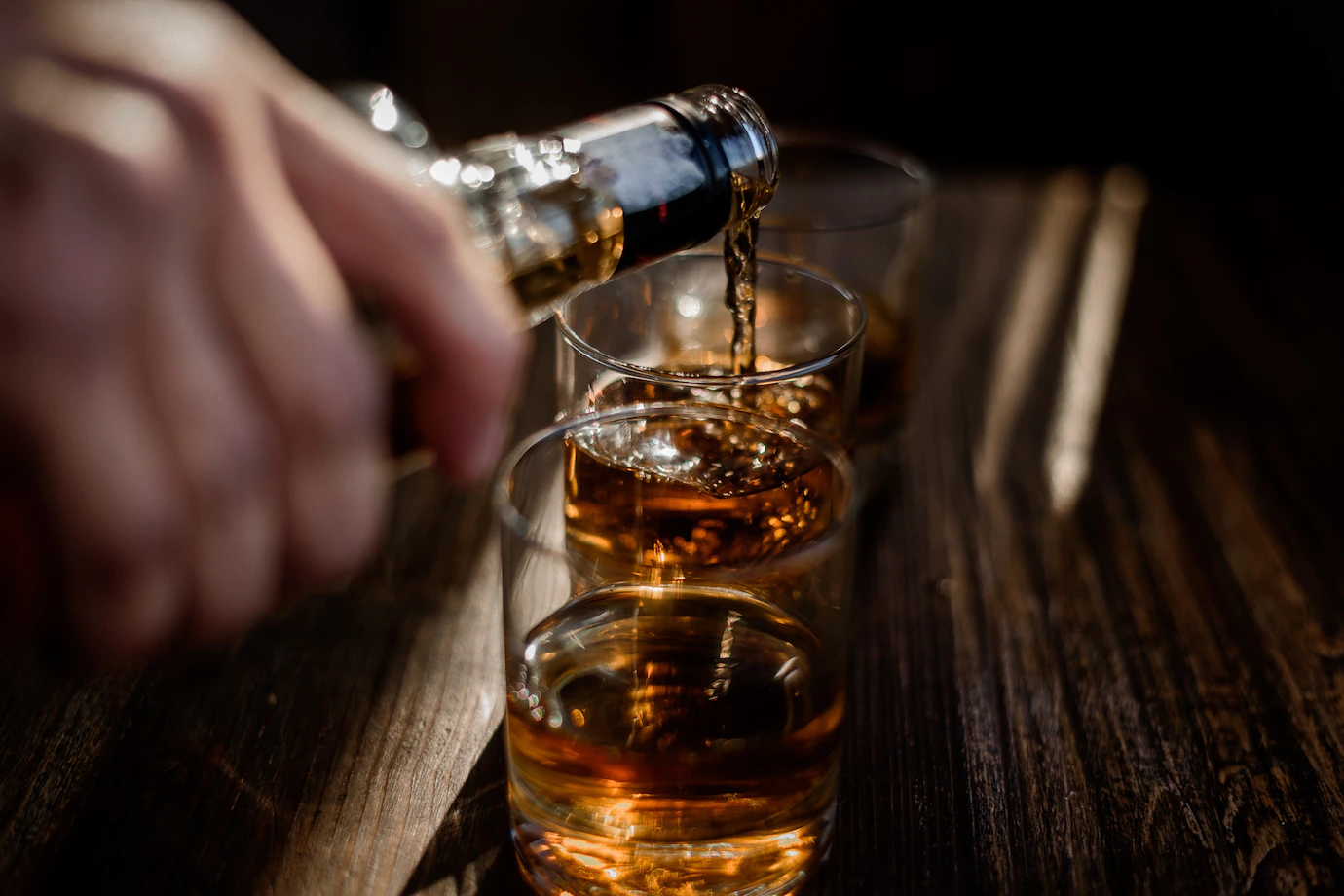 pouring-strong-alcohol-drink-into-glasses-which-are-wooden-table-8353-11029.webp
