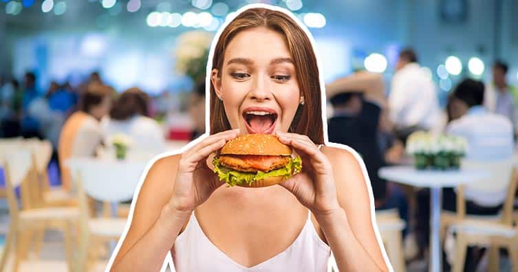 woman-eating-burger-restaurant-blue-background.jpg
