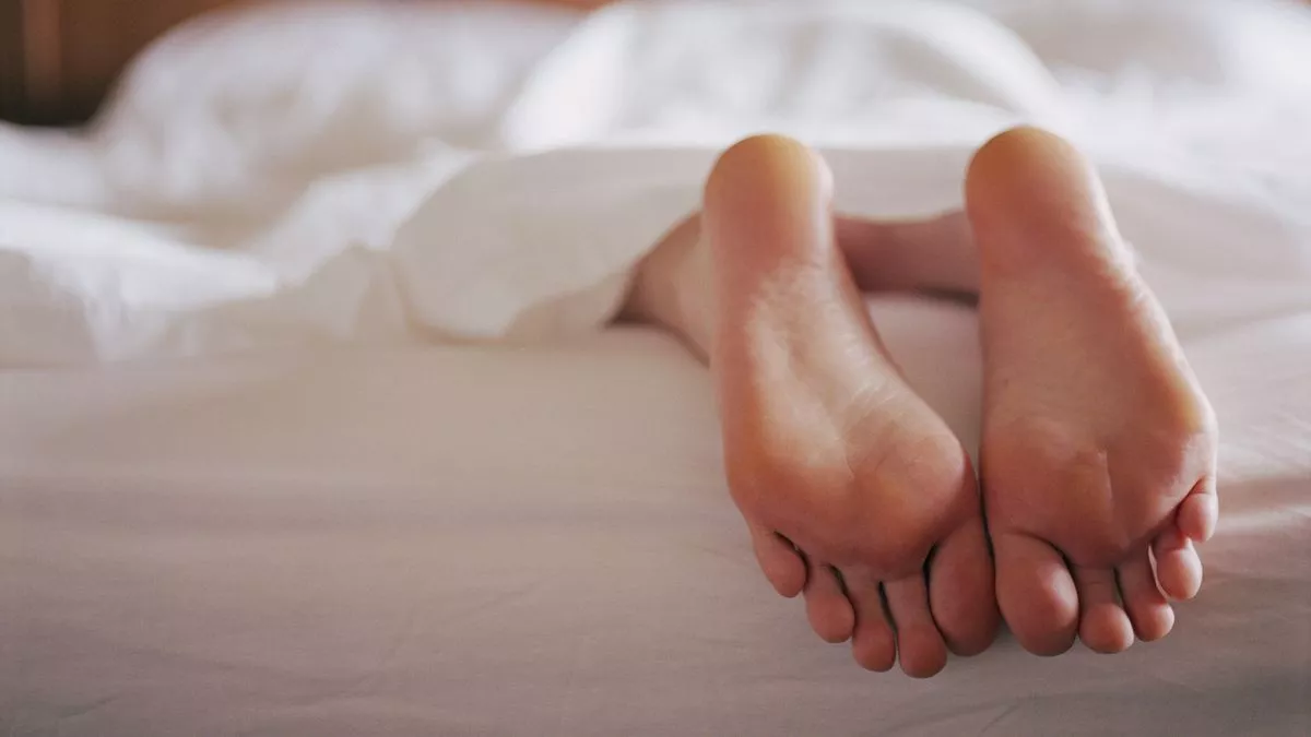 0-woman-lying-in-bed-under-sheet-focus-on-feet.webp