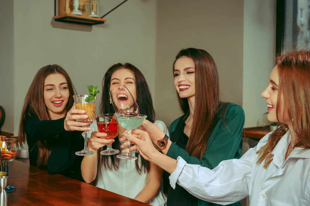female-friends-having-drinks-bar-they-are-sitting-wooden-table-with-cocktails-they-are-clinking-glasses-155003-22892.webp