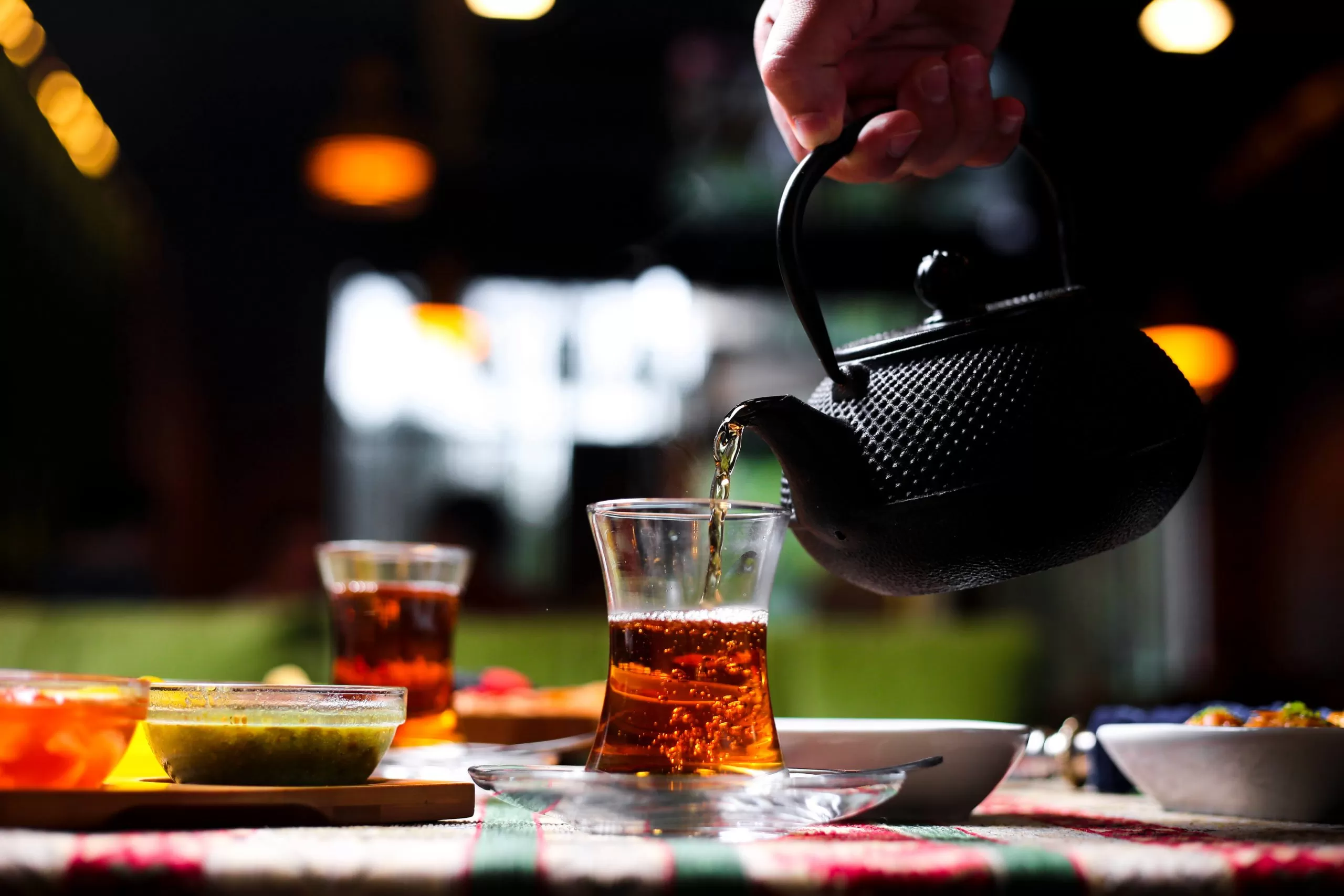 man-pouring-tea-into-armudu-glass-from-stone-teapot-2-scaled.webp