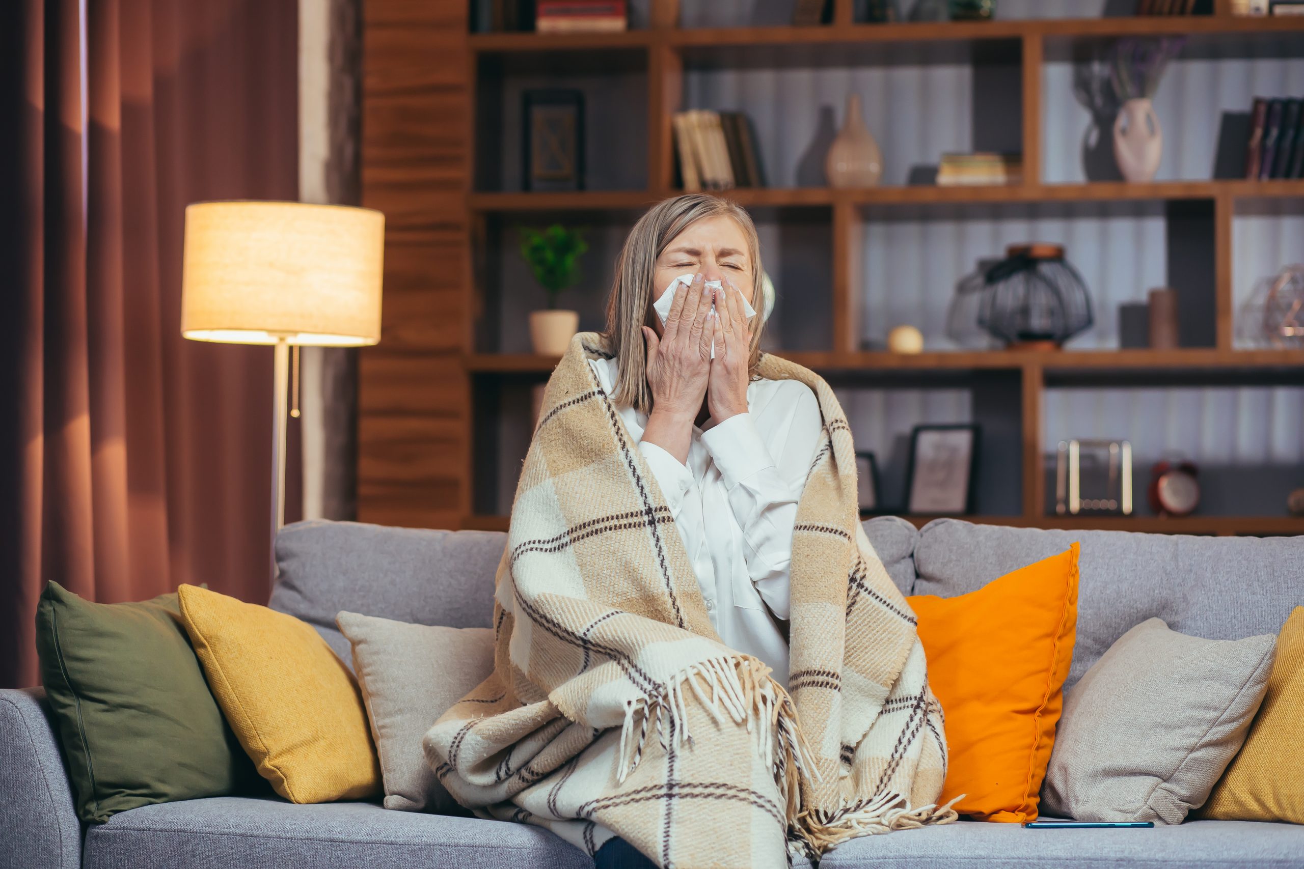 evening-older-woman-sits-couch-sick-sneezes-coughs-scaled.jpg