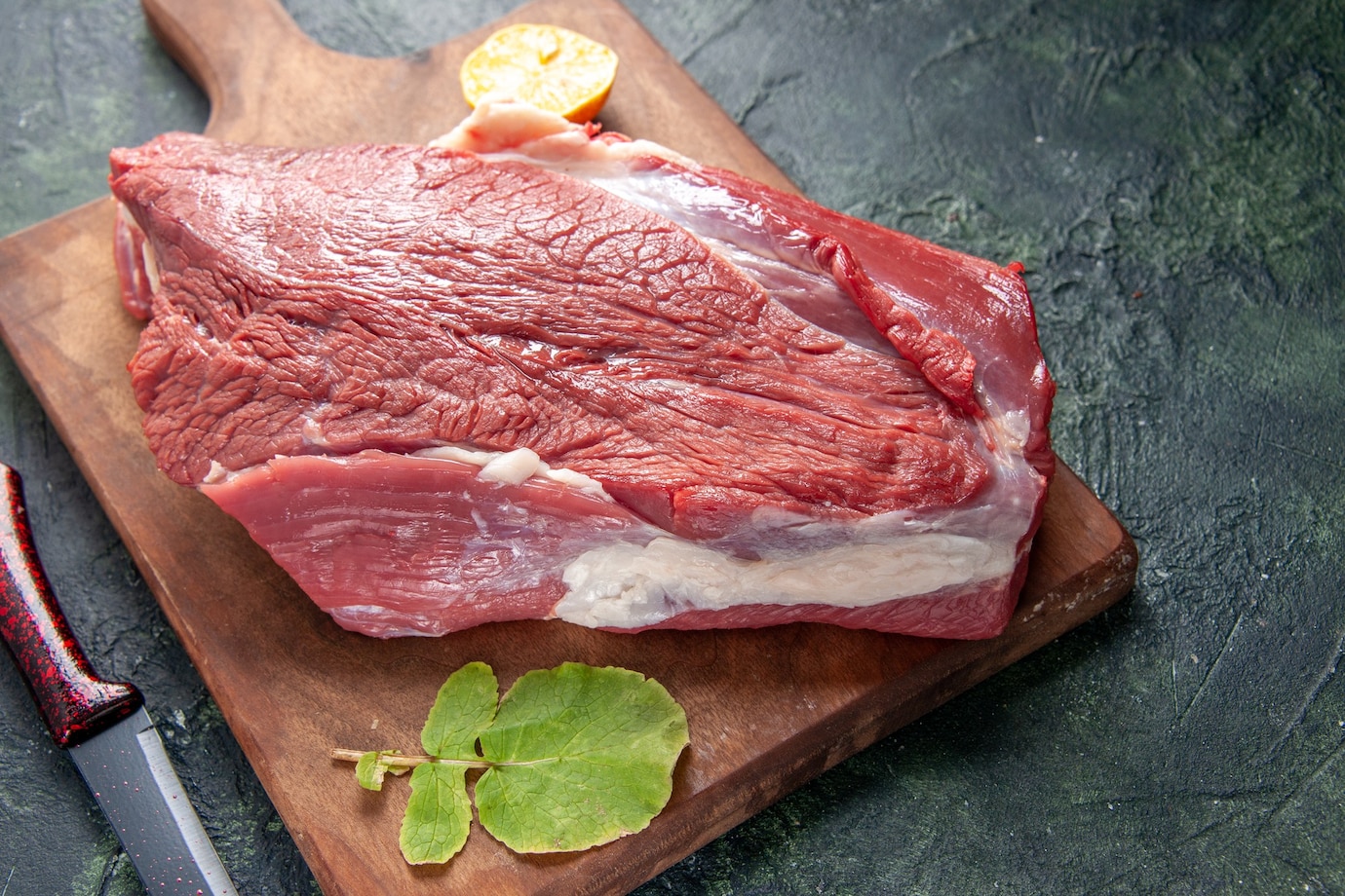close-up-view-fresh-raw-red-meats-lemon-brown-wooden-cutting-board-knife-dark-color-background-179666-46994.jpg