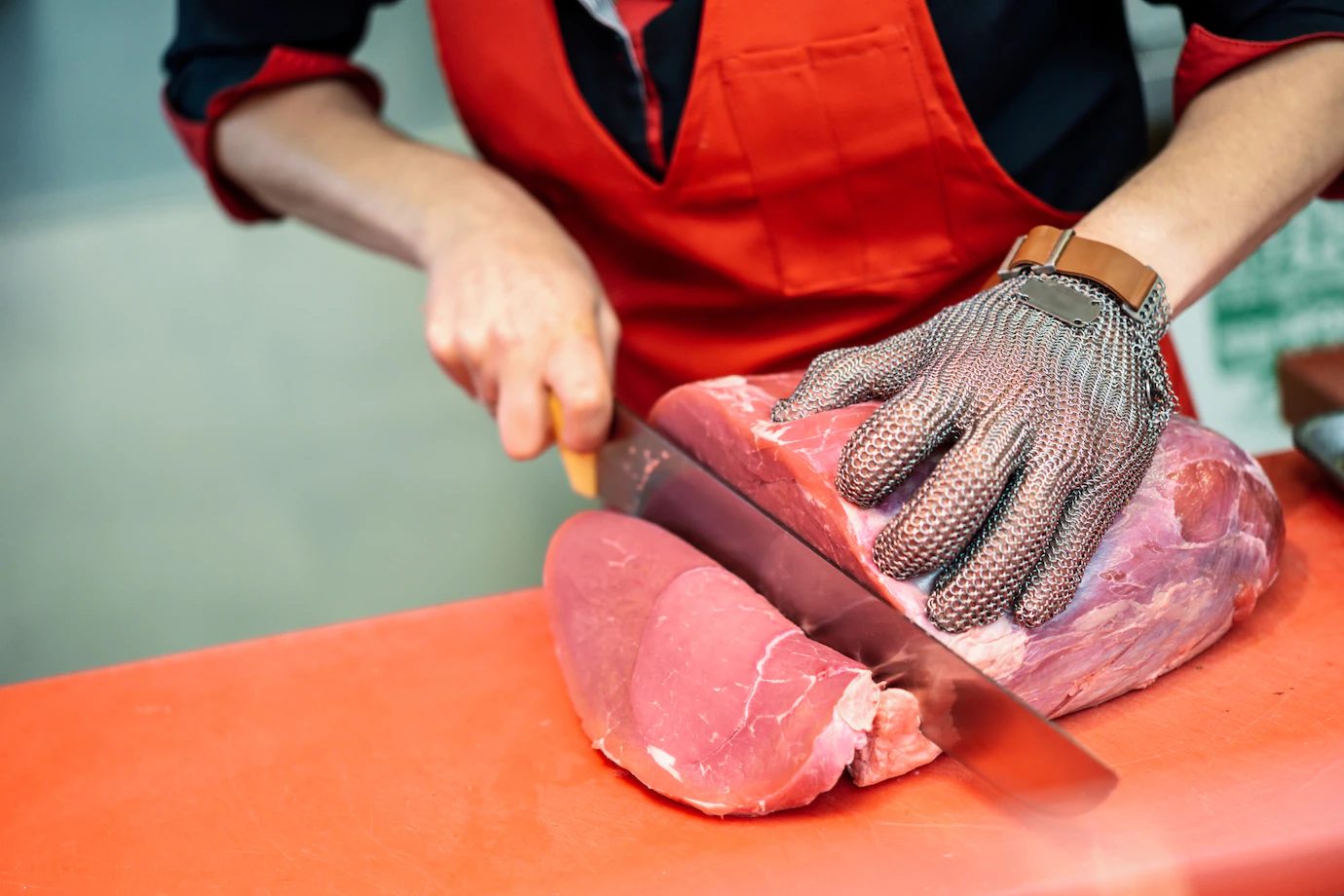 woman-cutting-fresh-meat-butcher-shop-with-metal-safety-mesh-glove-1139-1726.webp